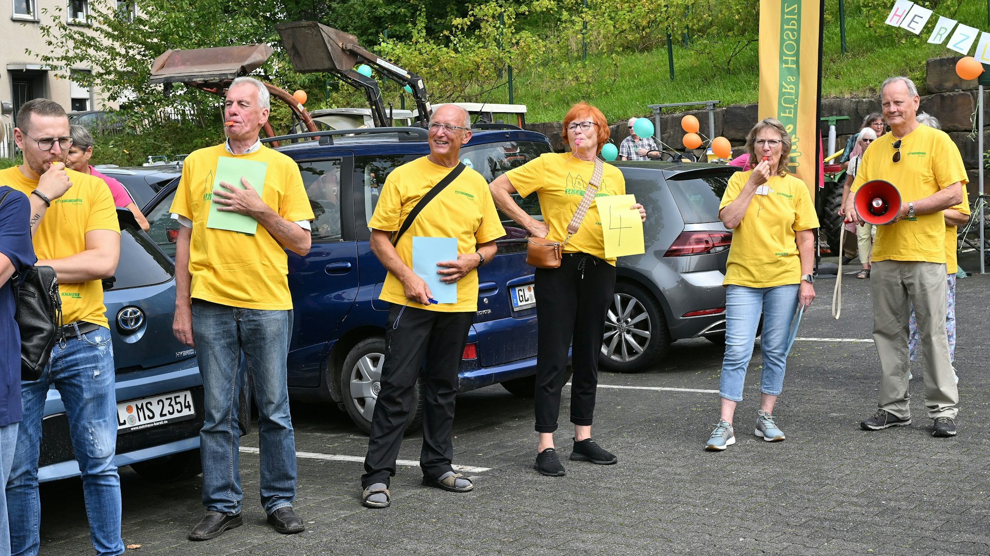 Menschen in gelben T-Shirts empfangen Heimkehrer auf einem Parkplatz.