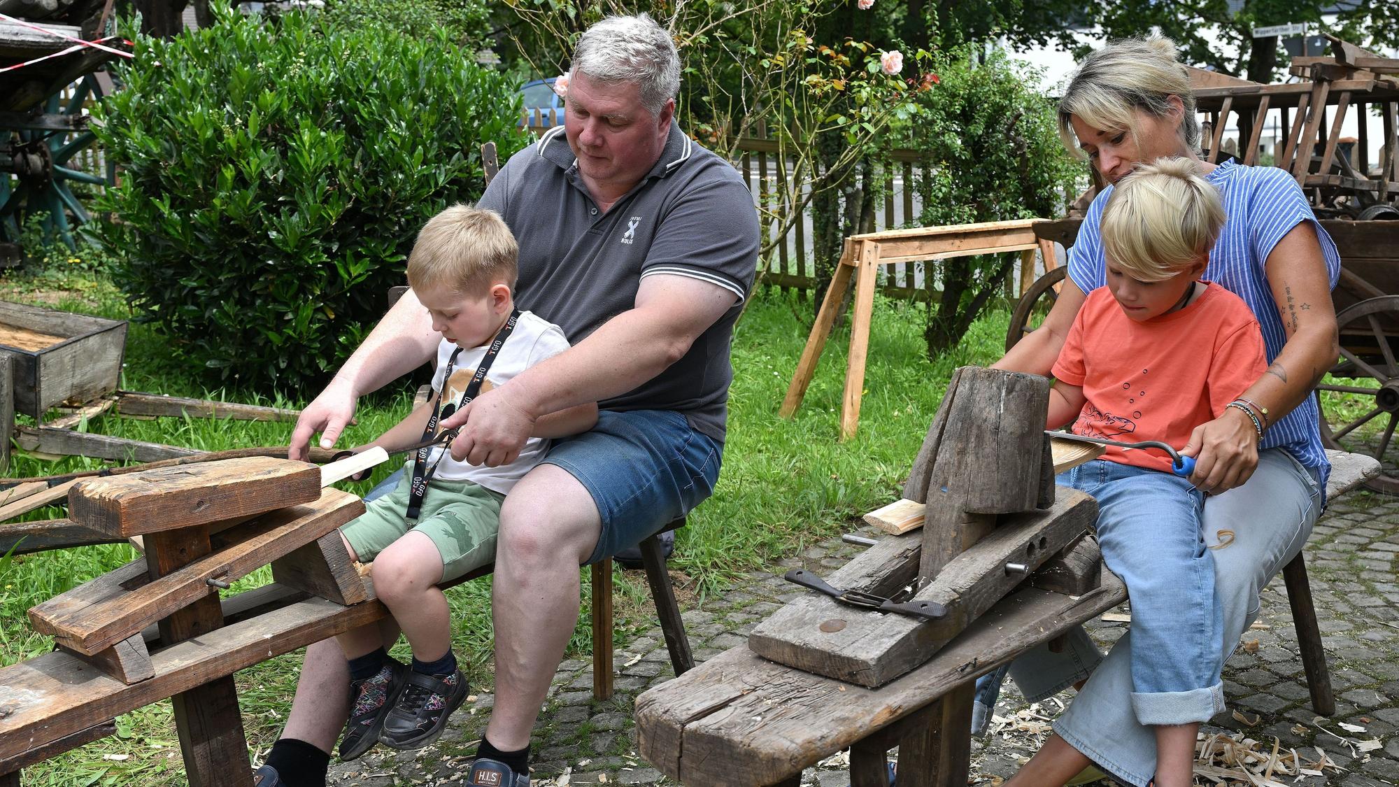 Erwachsene stellen mit Kindern Holzschindeln her.