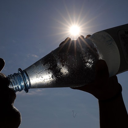 Eine Frau trinkt in der Sonne Mineralwasser.