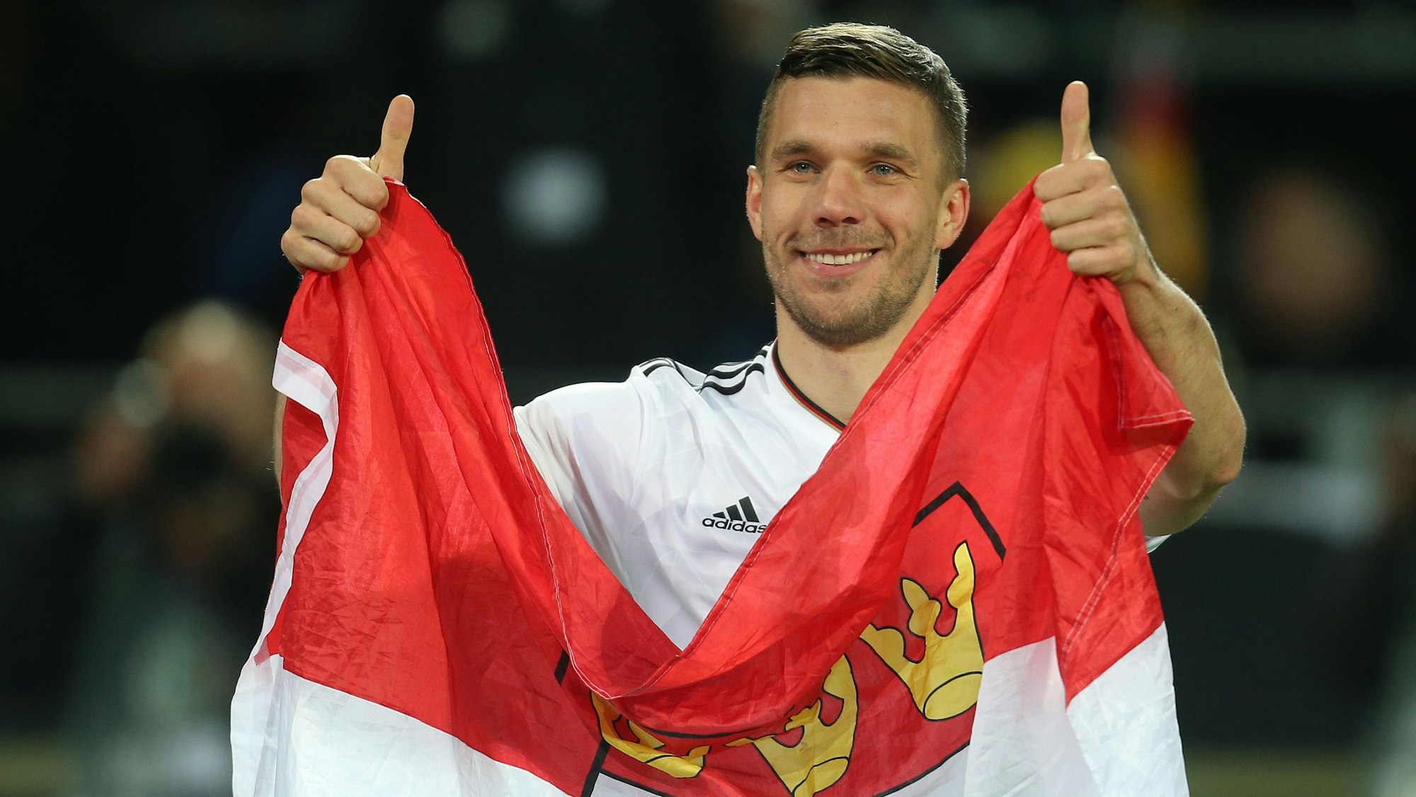 Lukas Podolski aus Deutschland verabschiedet sich im März 2017 in Dortmund von der Nationalmannschaft und hält dabei eine Kölner Fahne.