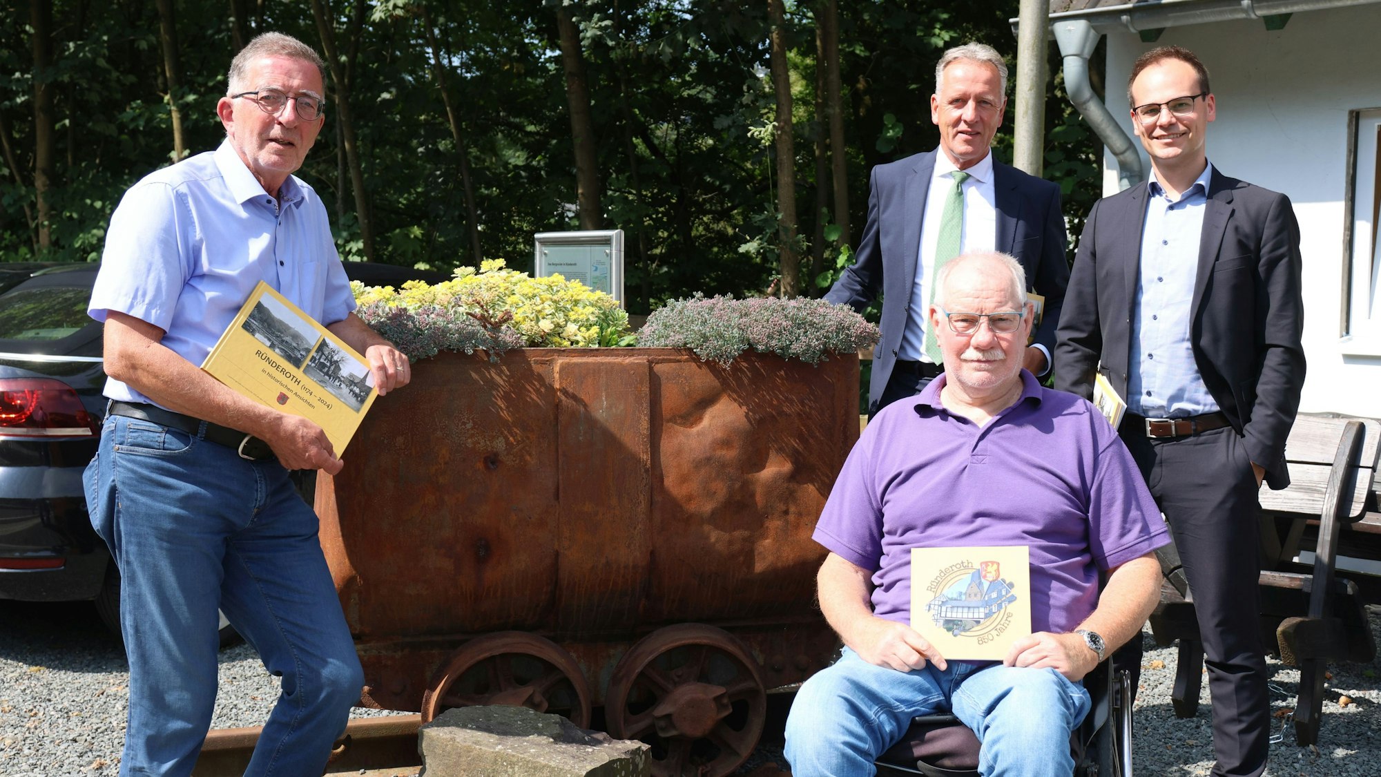 Vier Männer stehen zu einem Gruppenfoto zusammen und präsentieren einen historischen Bildband über den Ort Ründeroth.