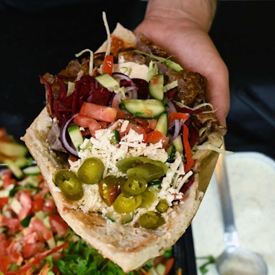 Eine Dönertasche wird mit Salat gefüllt.