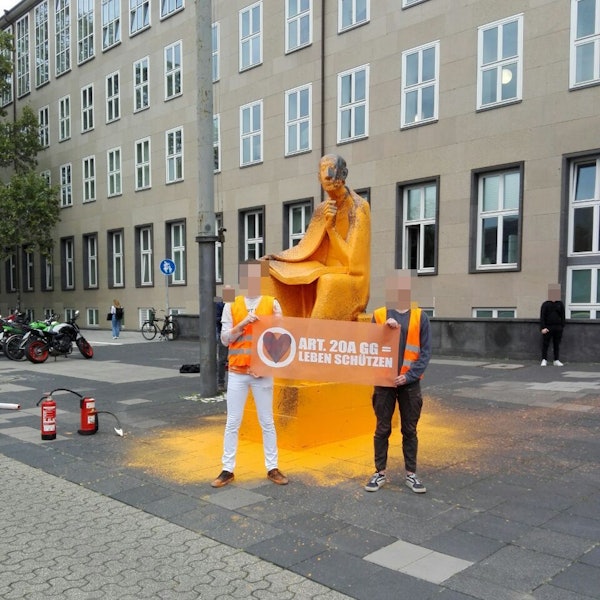 Mitglieder der Letzten Generation vor dem besprühten Albertus-Magnus-Denkmal