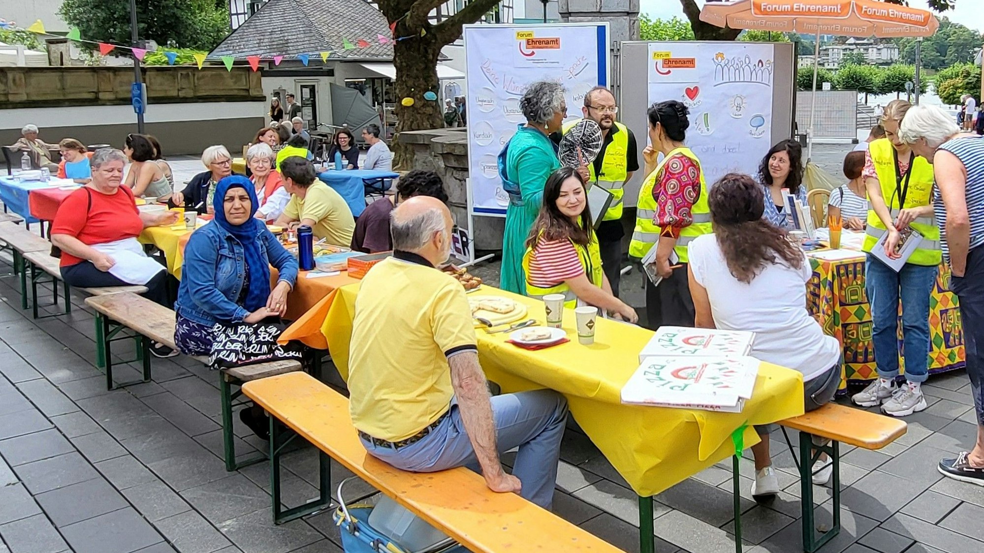Menschen sitzen an Tischen auf dem Marktplatz.