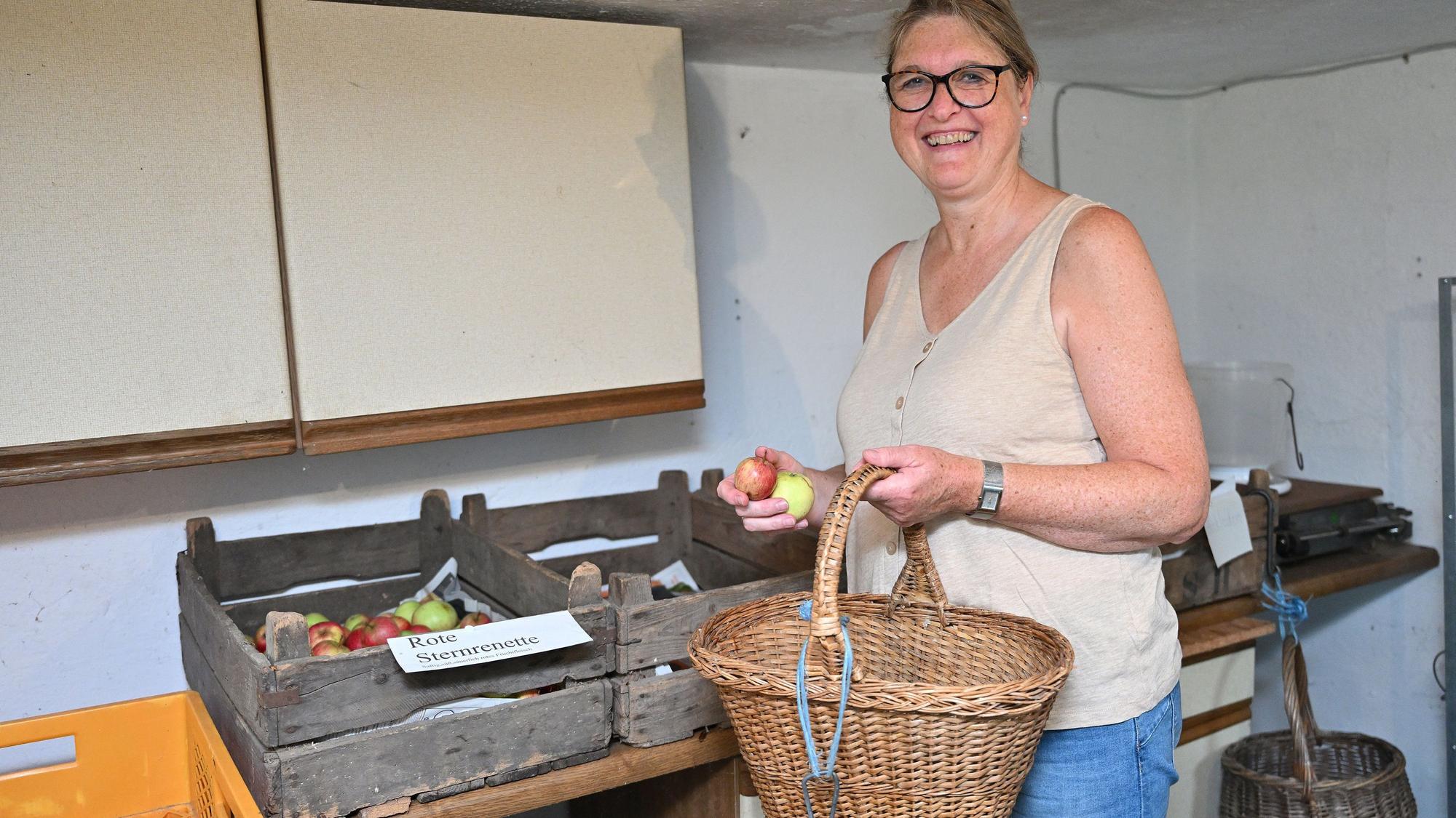 Petra Thomas sortiert Obst in Kisten ein.