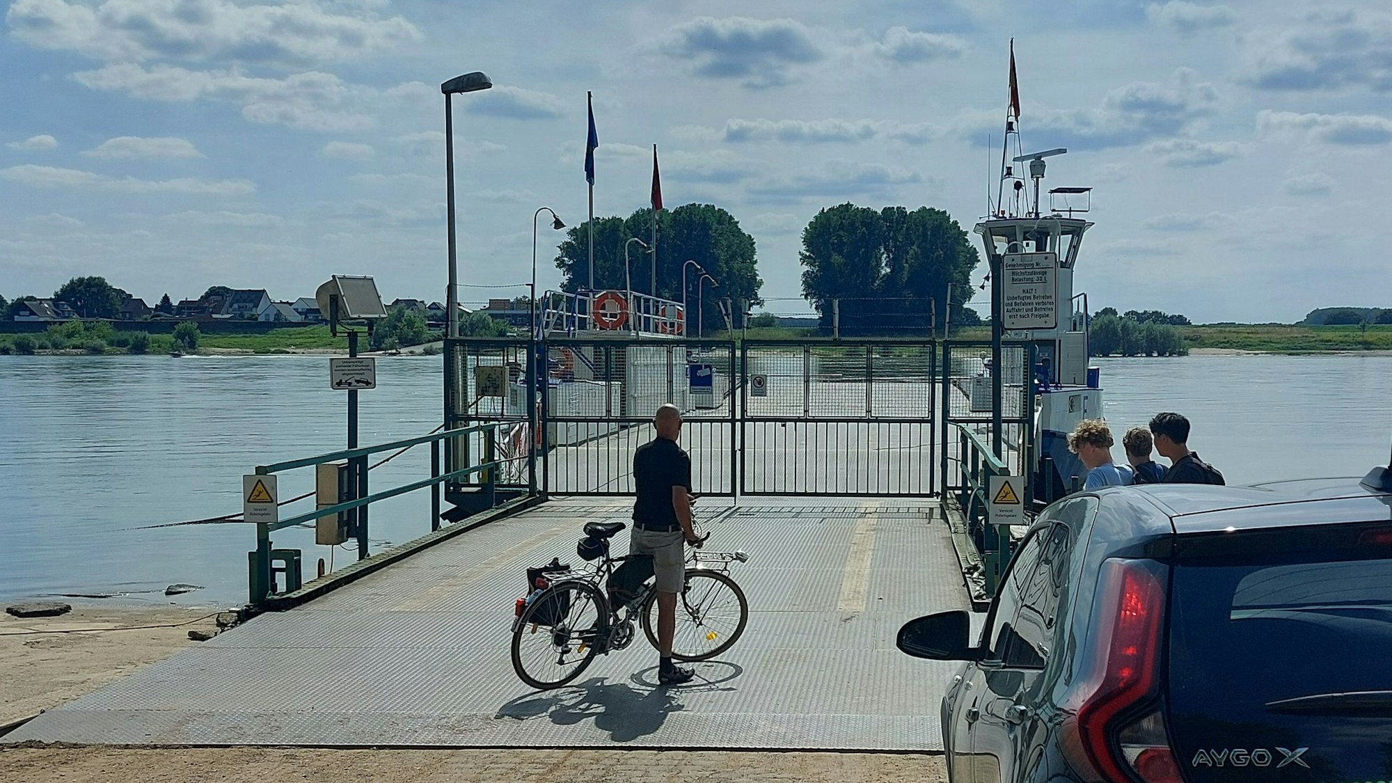 Ein Radler und ein Auto stehen vor dem geschlossenen Fähranleger in Hitdorf.