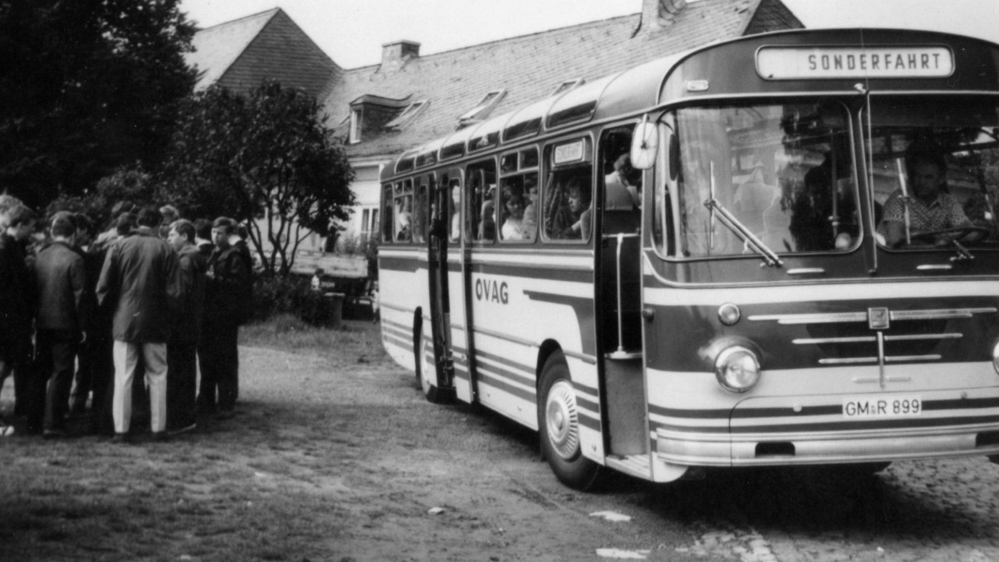 Zu sehen ist ein Bus, vor dem sich eine Menschengruppe versammelt hat.