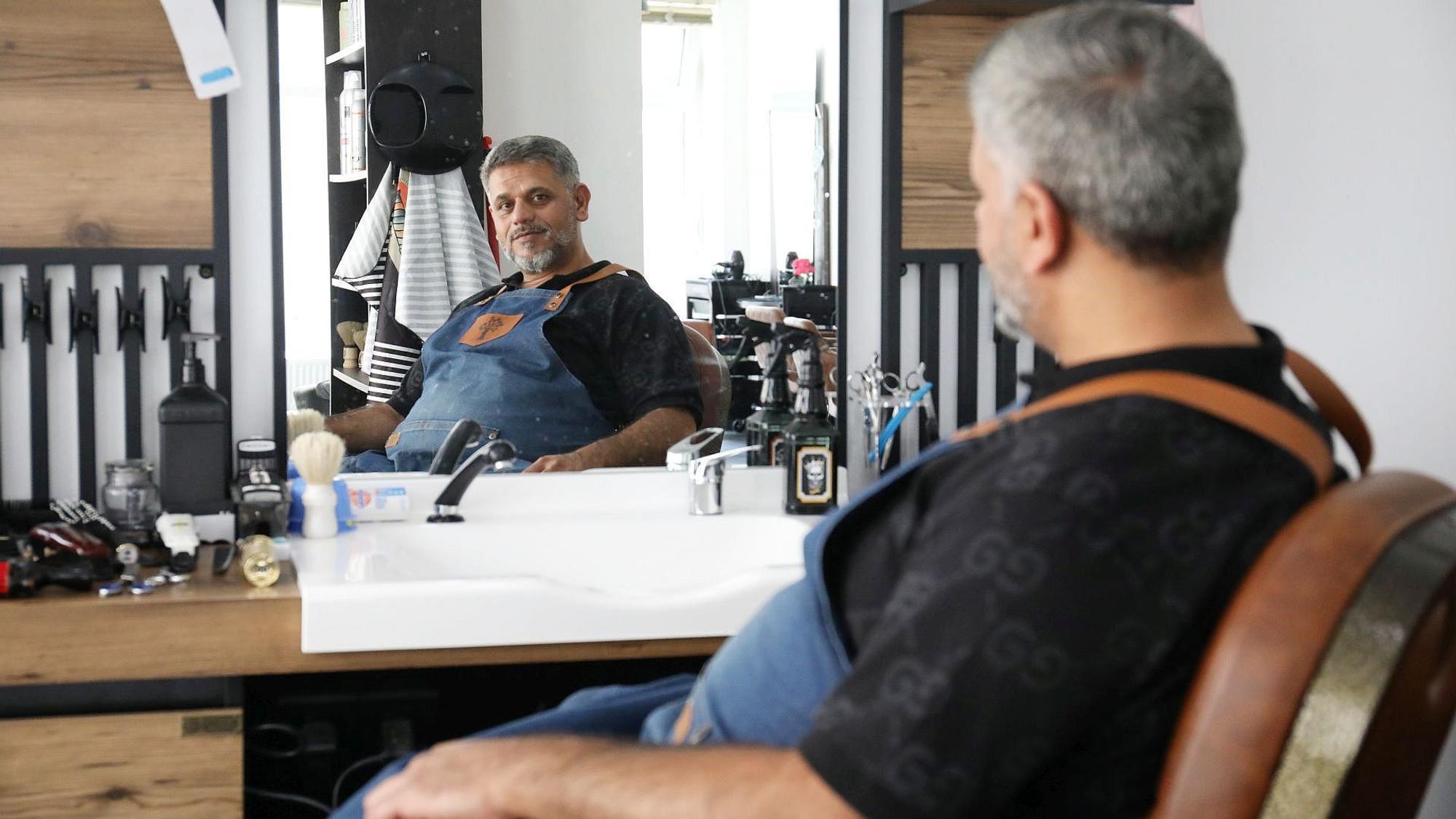 Ein Mann sitzt in einem Friseursalon vor dem Spiegel