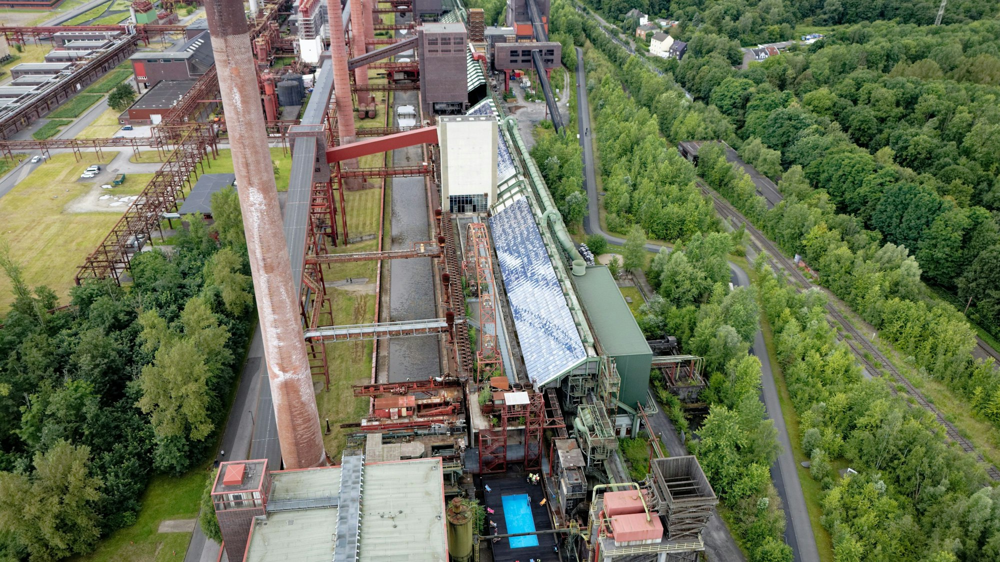 Das Werksschwimmbad der Zeche Zollverein leuchtet aus der Luft gesehen blau zwischen der Industriearchitektur.