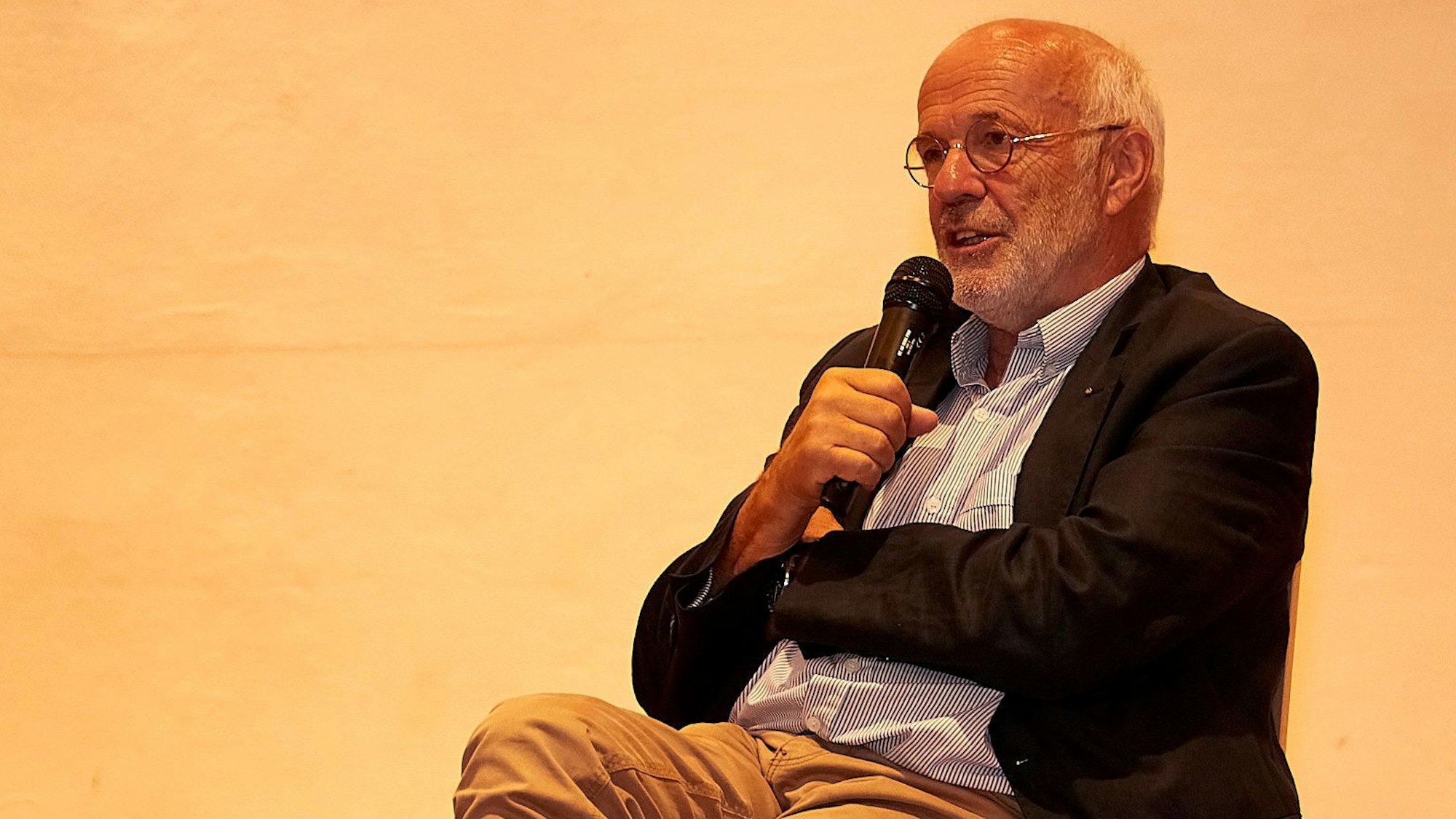 Tierarzt Dr. Michael Weiler sitzt auf einem Stuhl und spricht in ein Mikrofon.