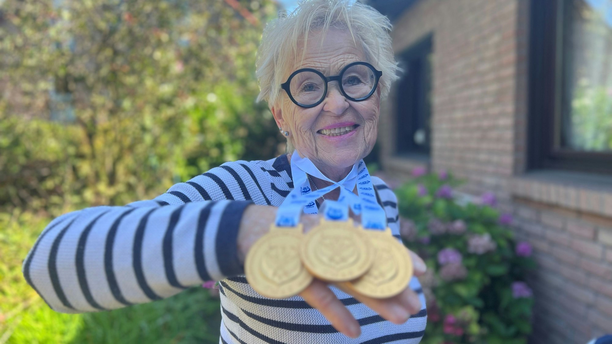 Hannelore Becker hält drei Gold-Medaillien in der Hand.