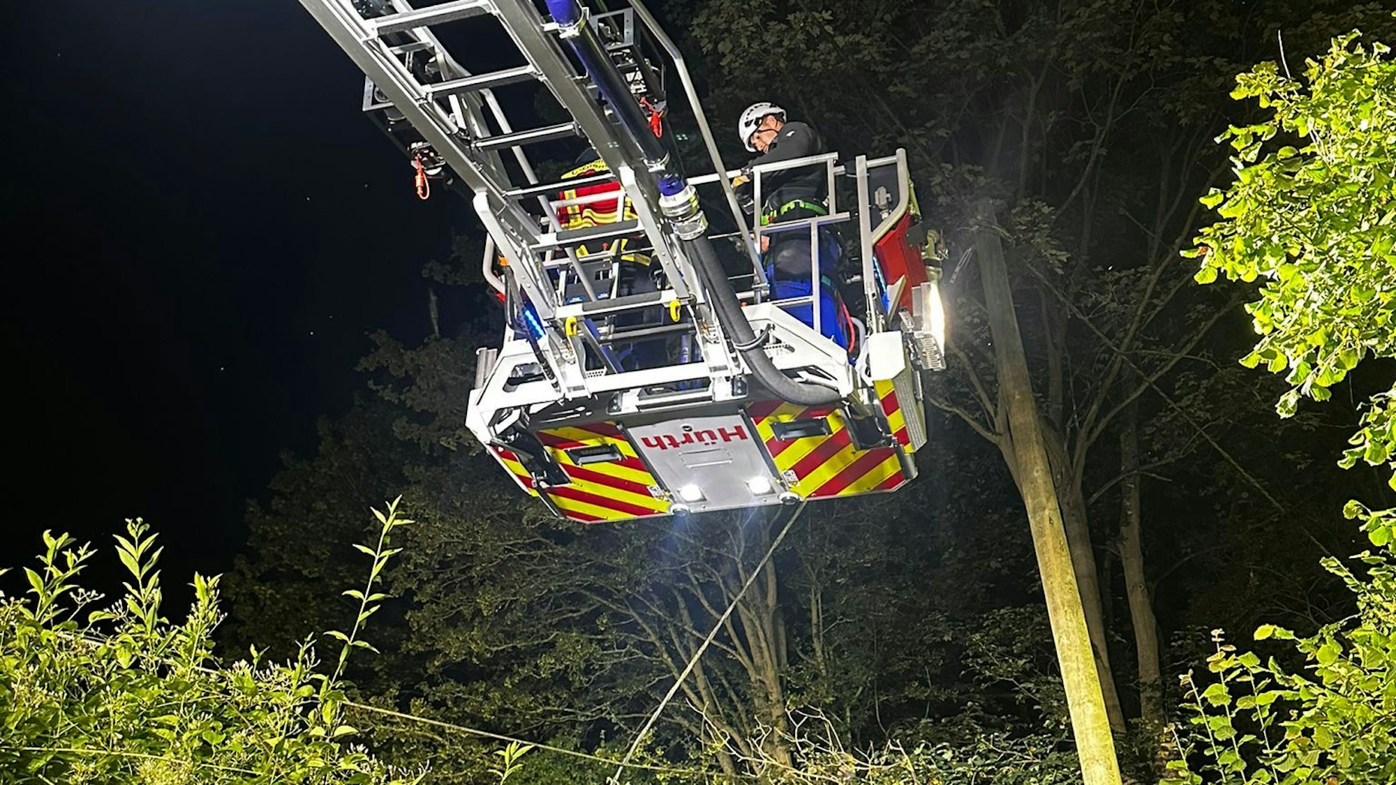 Ein Feuerwehrmann steht im Korb einer Drehleiter.