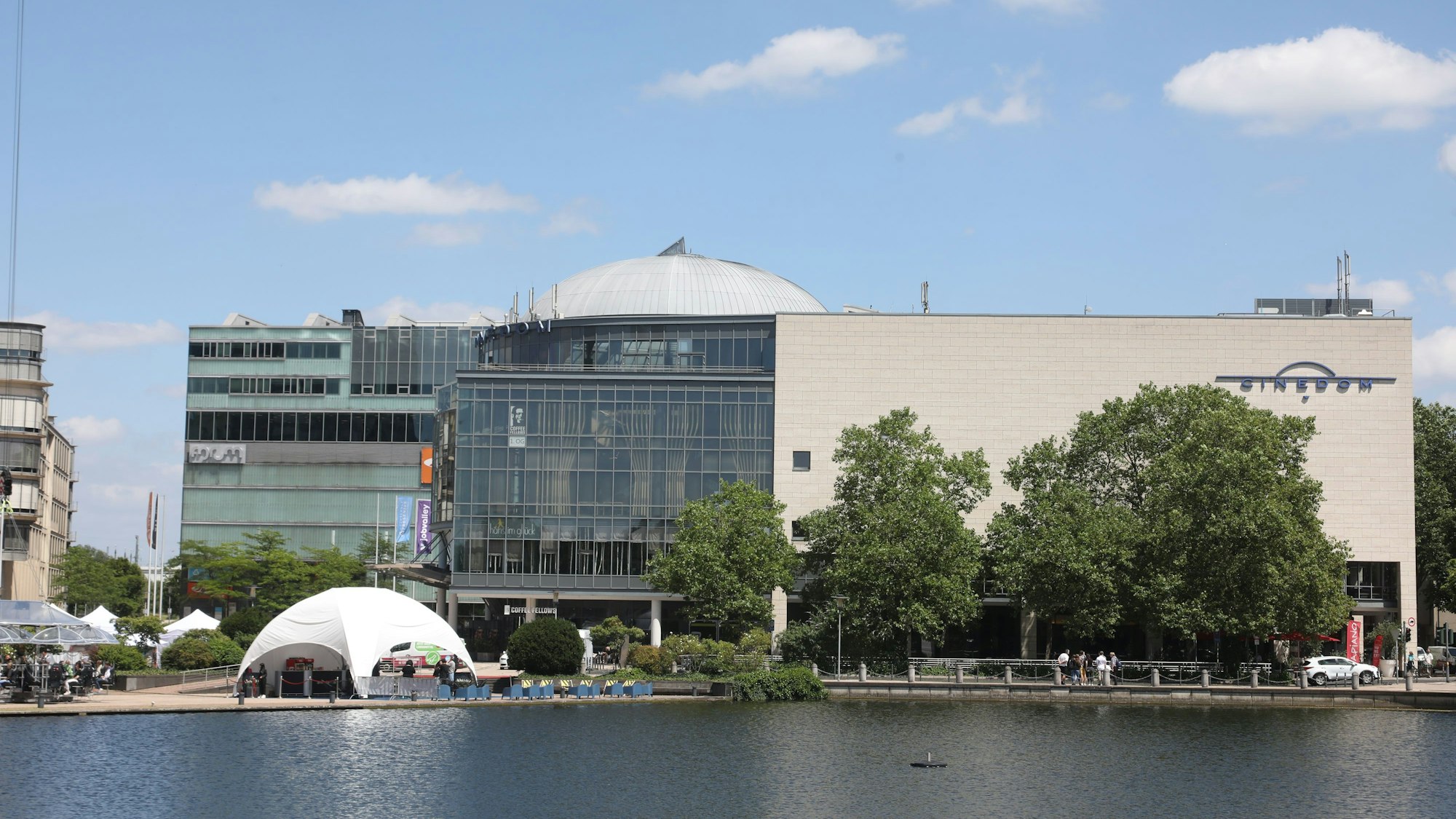 28.06.2024, Köln: Das Cinedom am Mediapark ist ein Multiplex Kino. Davor ist der Weiher im Mediapark zu sehen.