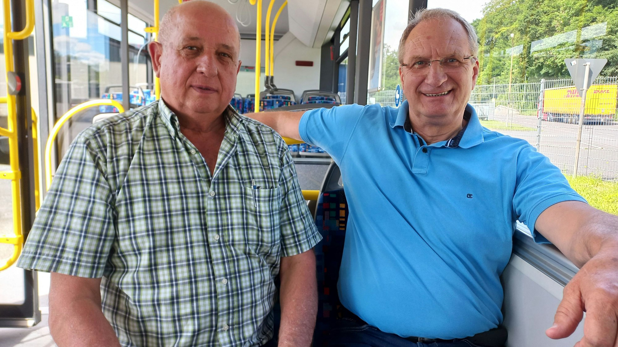 Zu sehen sind zwei Männer, die in einem Linienbus sitzen.