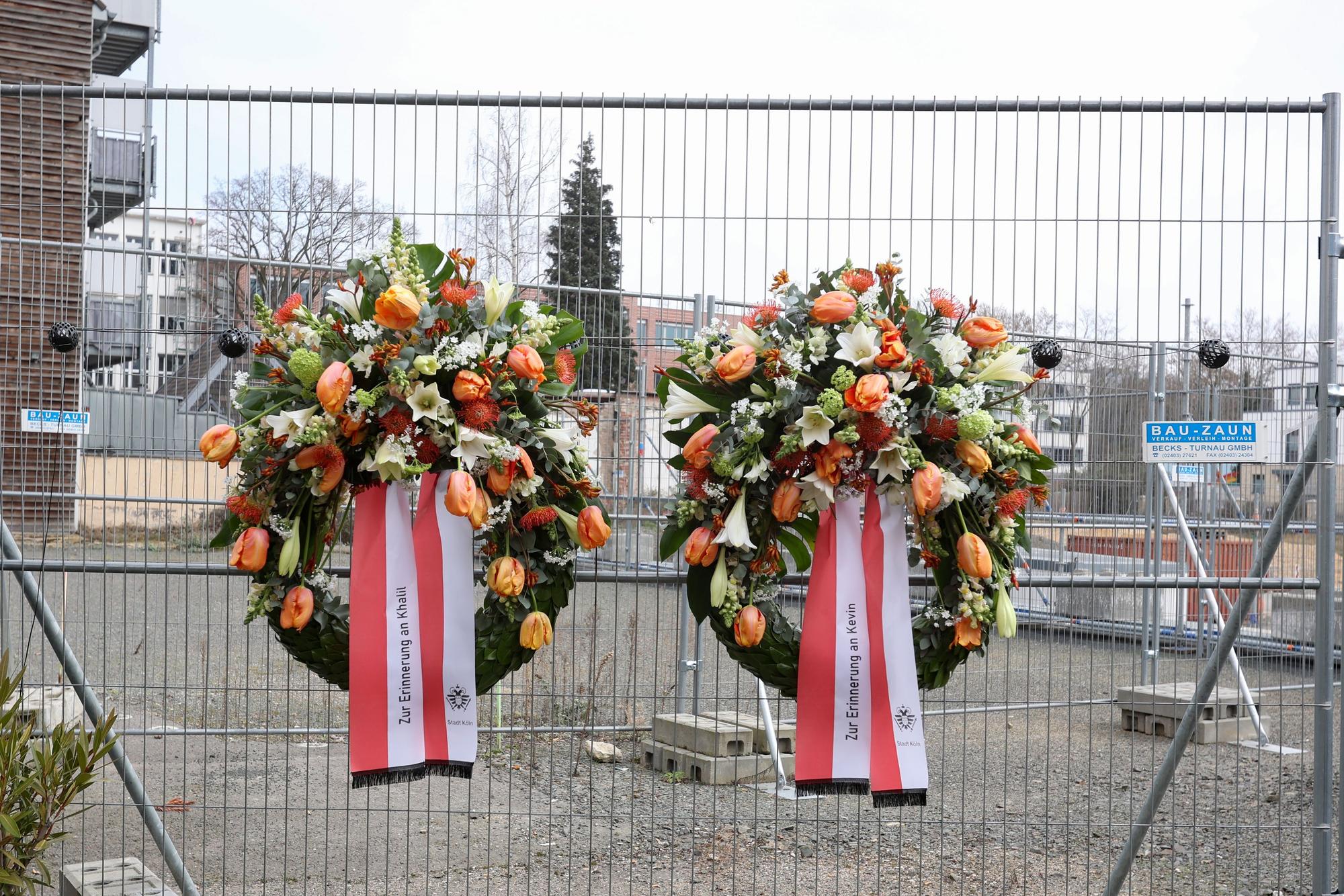 Zwei Kränze hängen an einem Bauzaun.