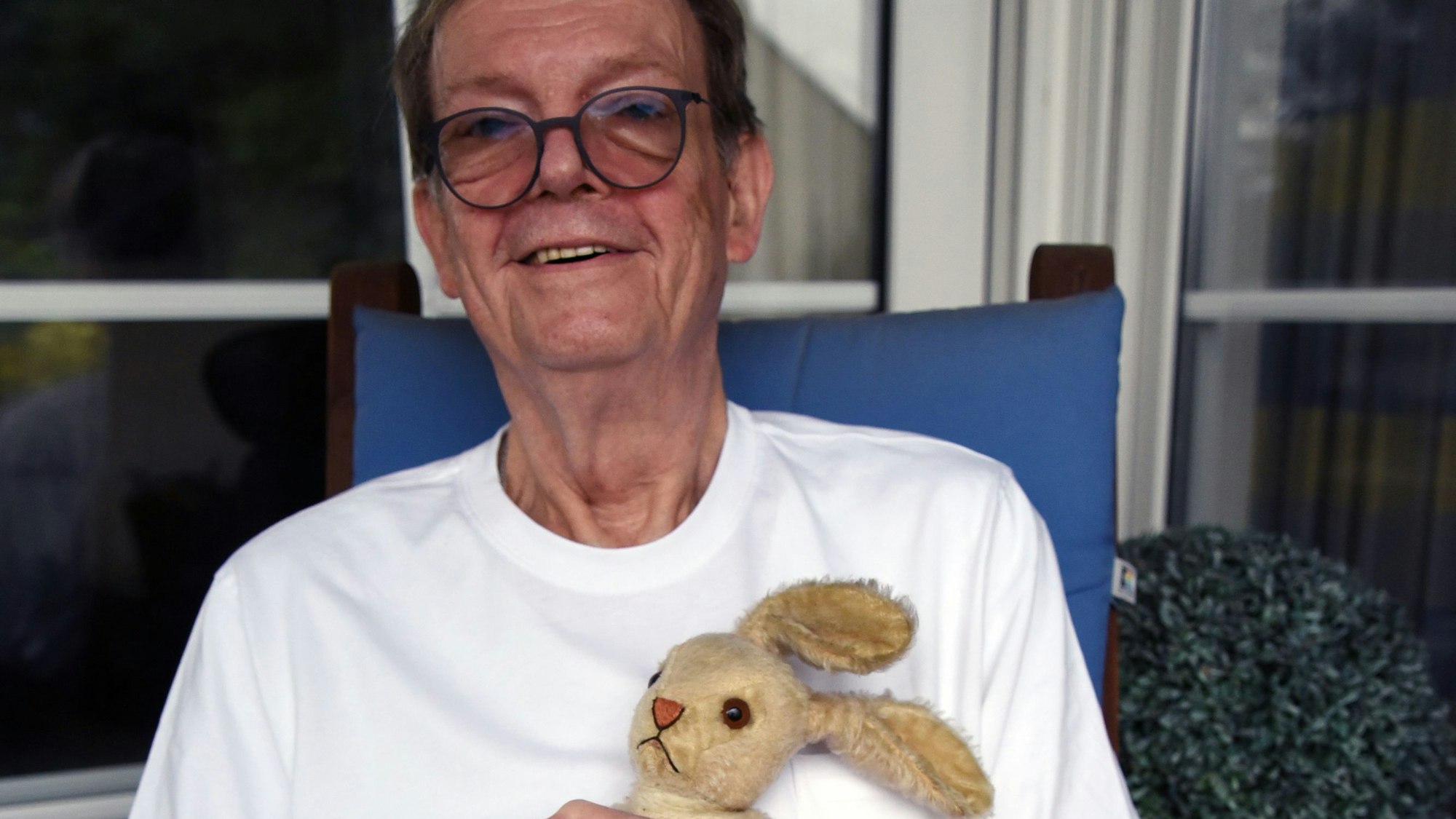 Zu sehen ist ein Mann, der einen Plüschhasen im Arm hält.