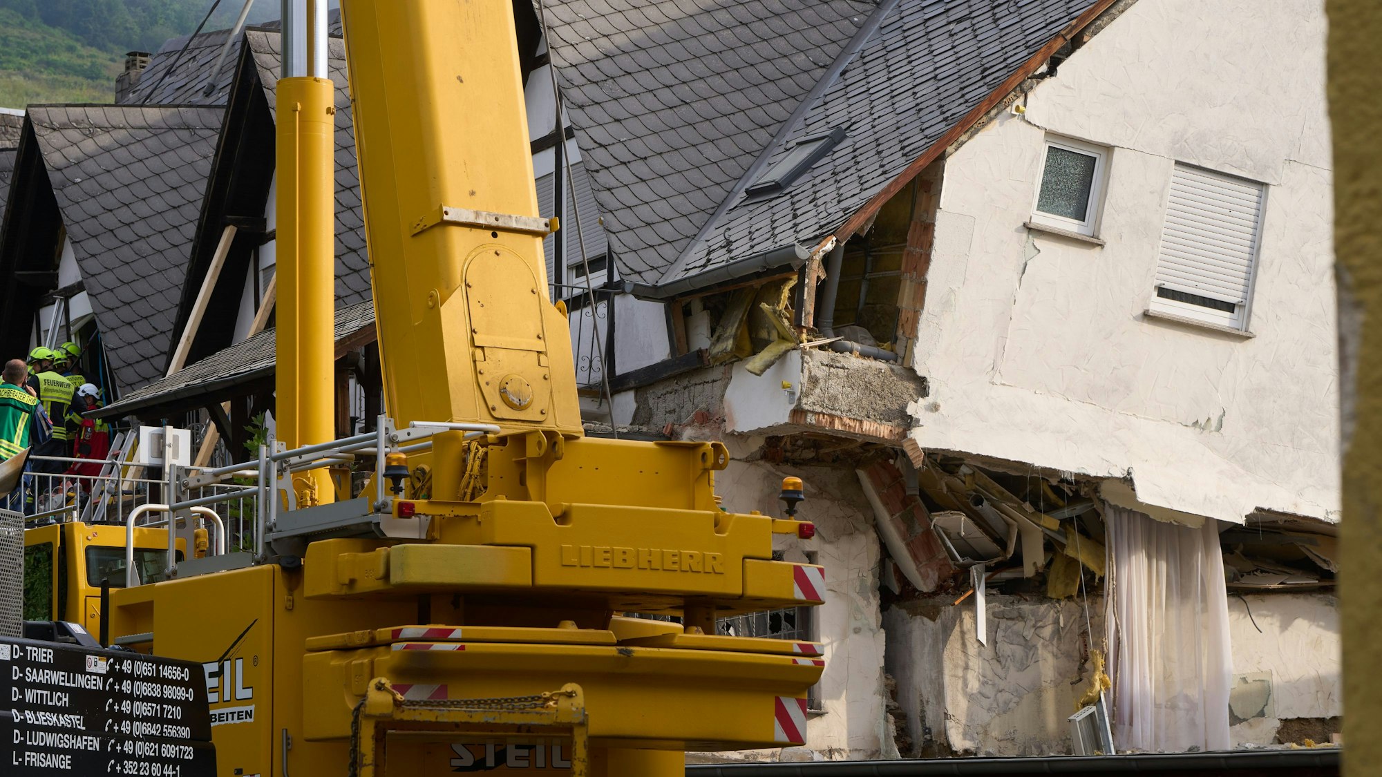 Feuerwehrleute bergen Verschüttete nach dem teilweisen Einsturz eines Hotels. Ein Kran steht vor dem eingestürzten Haus, die