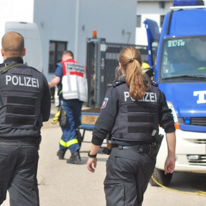 Zwei Polizisten und ein THW-Helfer gehen am 27. April 2022 auf ein Gebäude zu. Darin wird eine Cannabis-Plantage sichergestellt.