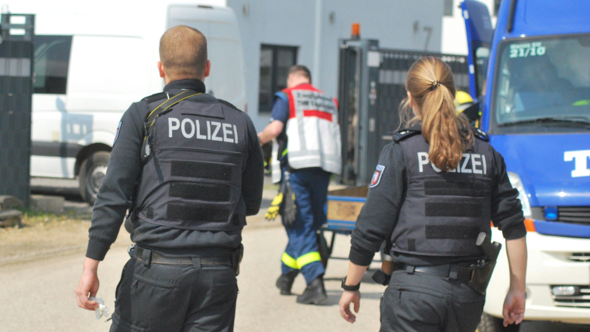 Zwei Polizisten und ein THW-Helfer gehen am 27. April 2022 auf ein Gebäude zu. Darin wird eine Cannabis-Plantage sichergestellt.