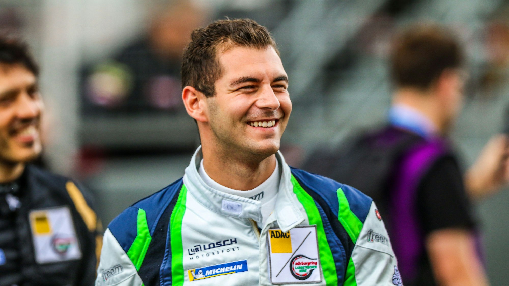 Rennfahrer Tobias Müller trägt seinen Rennoverall und lacht.