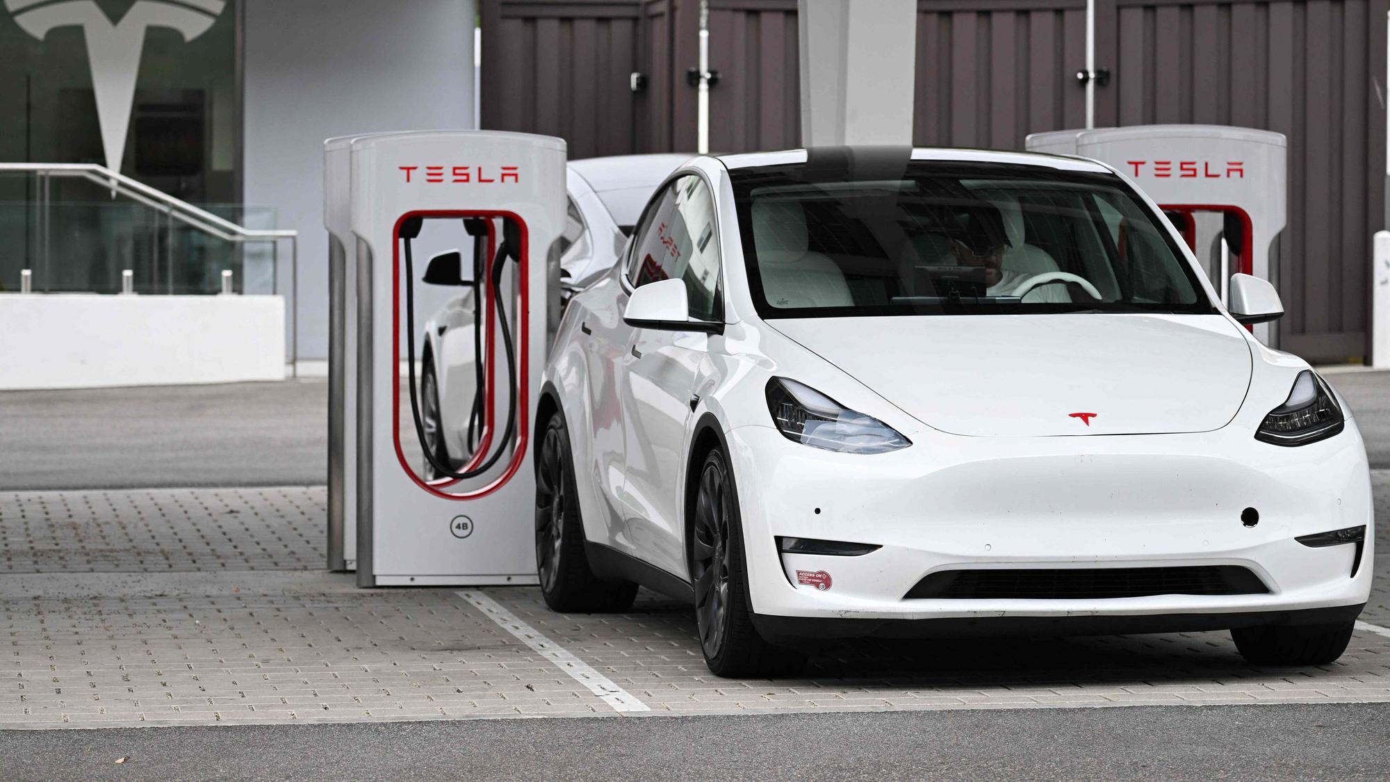 (FILES) A Tesla electric vehicle charges at a Tesla Supercharger location in Santa Monica, California on May 15, 2024. Tesla reported a hefty drop in second-quarter profits on July 23, 2024 due to the effect of price cuts while spending aggressively on artificial intelligence and other technology. Elon Musk's electric vehicle company reported profits of $1.5 billion, down 45 percent, on revenues of $25.5 billion, up two percent. (Photo by Patrick T. Fallon / AFP)