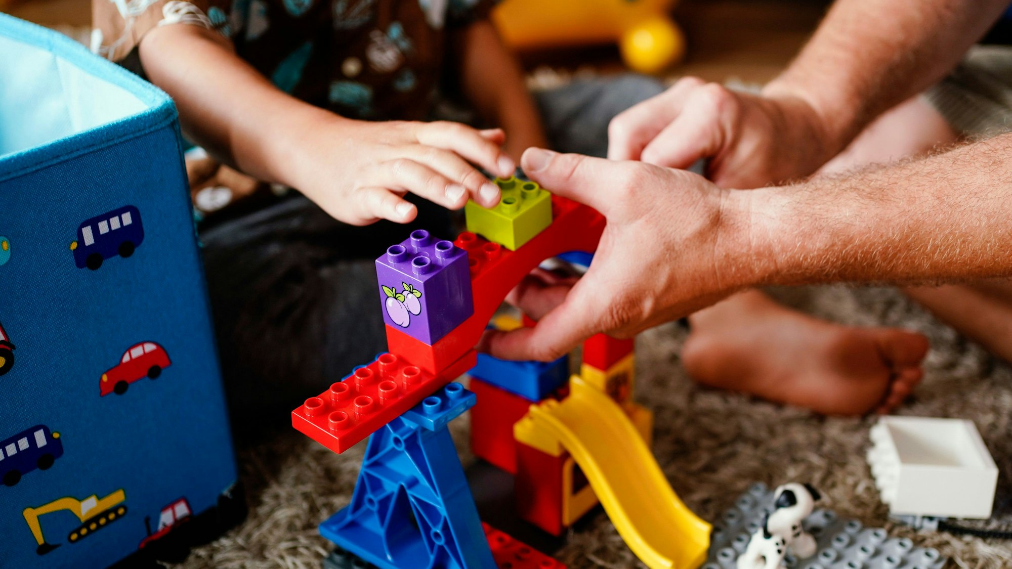 Ein erwachsener Mensch und ein Kind bauen gemeinsam mit Bausteinen.