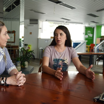 Zwei Frauen im Gespräch an einem Tisch.