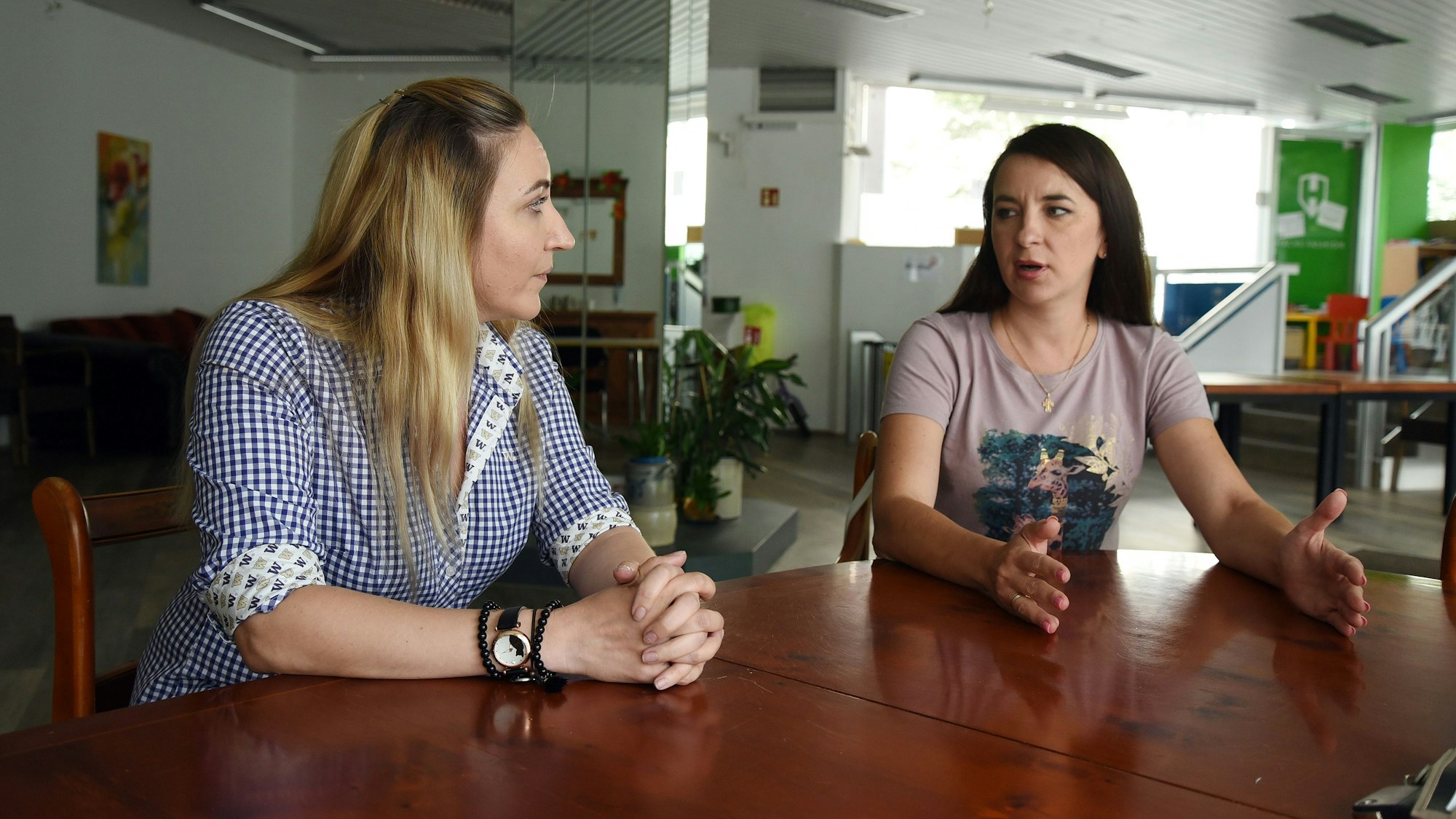 Zwei Frauen im Gespräch an einem Tisch.