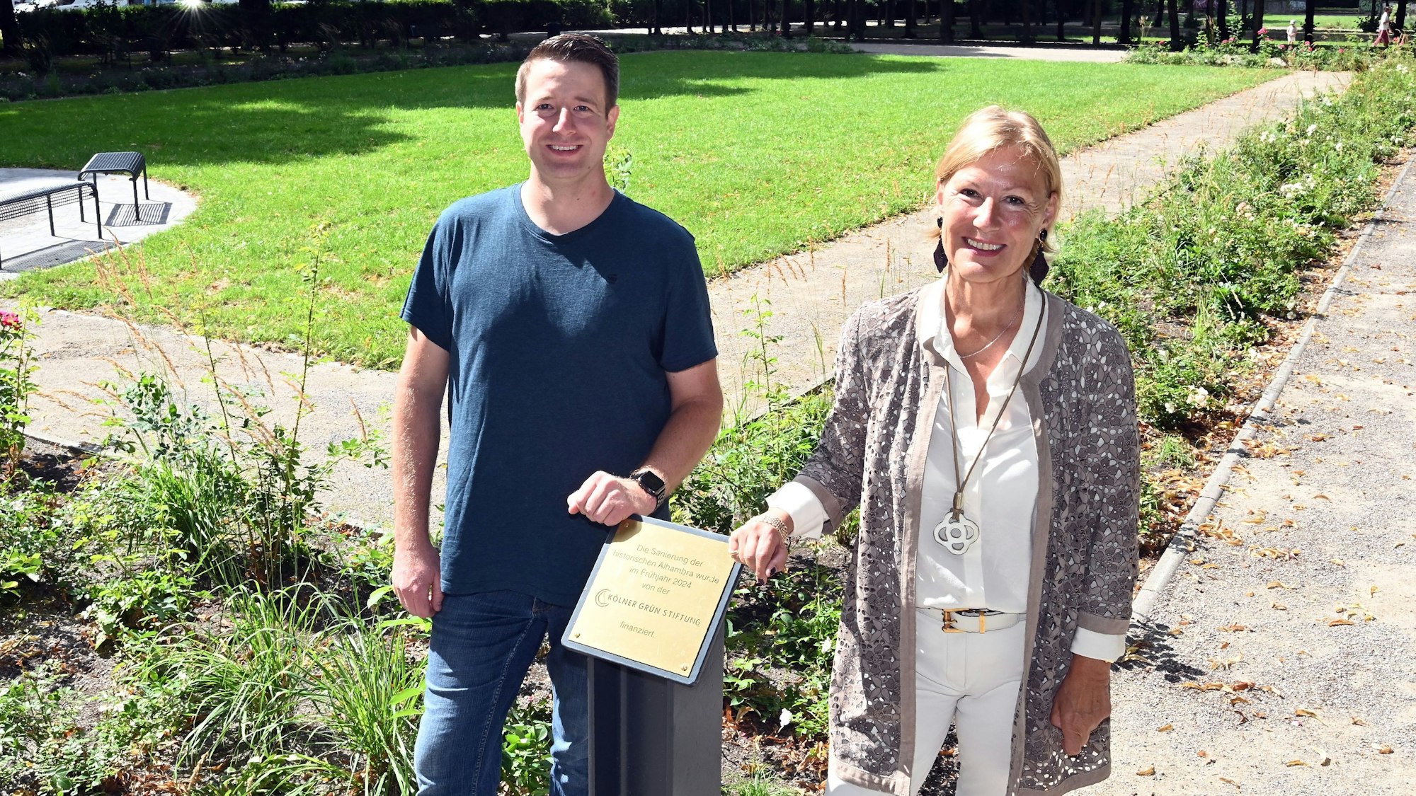 Zu sehen sind Maurice Wirtz und Beatrice Bülter, die vor Blumenbeeten in der Alhambra in Köln-Nippes stehen.