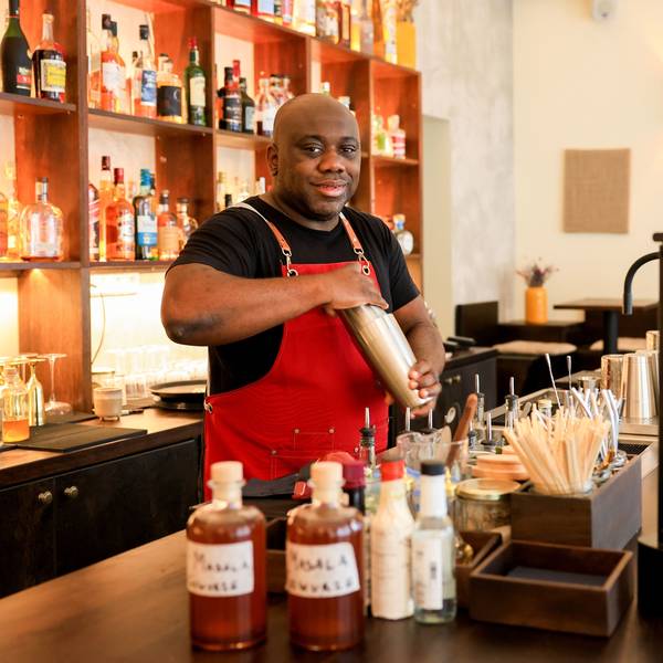 Barchef Samuél Antonio Bernardo steht an der Bar und hat einen Shaker in der Hand. Er lächelt in die Kamera.