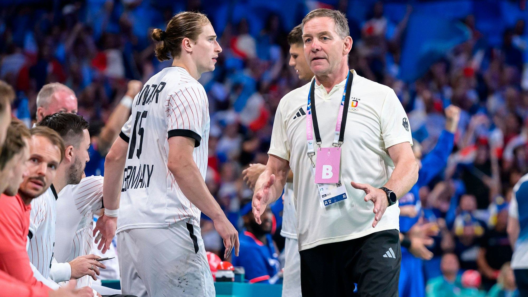DHB-Star Juri Knorr und Trainer Alfred Gislason während des Olympischen Viertelfinals gegen Frankreich am Spielfeldrand.