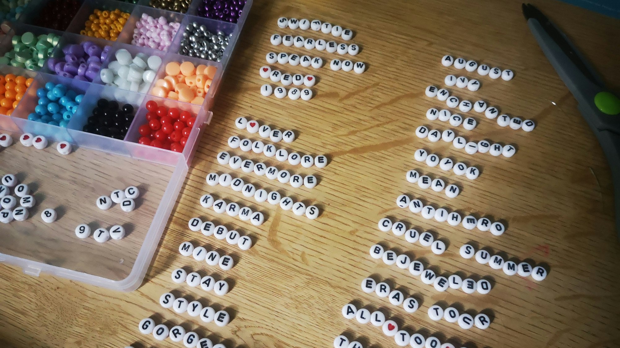 Perlen und Buchstaben für Freundschaftsbänder liegen ordentlich aufgereiht auf dem Couchtisch.