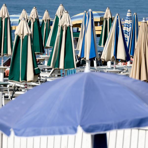 Sonnenschirme stehen geschlossen am Strand.