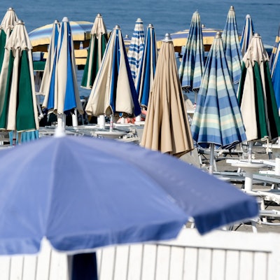 Sonnenschirme stehen geschlossen am Strand.