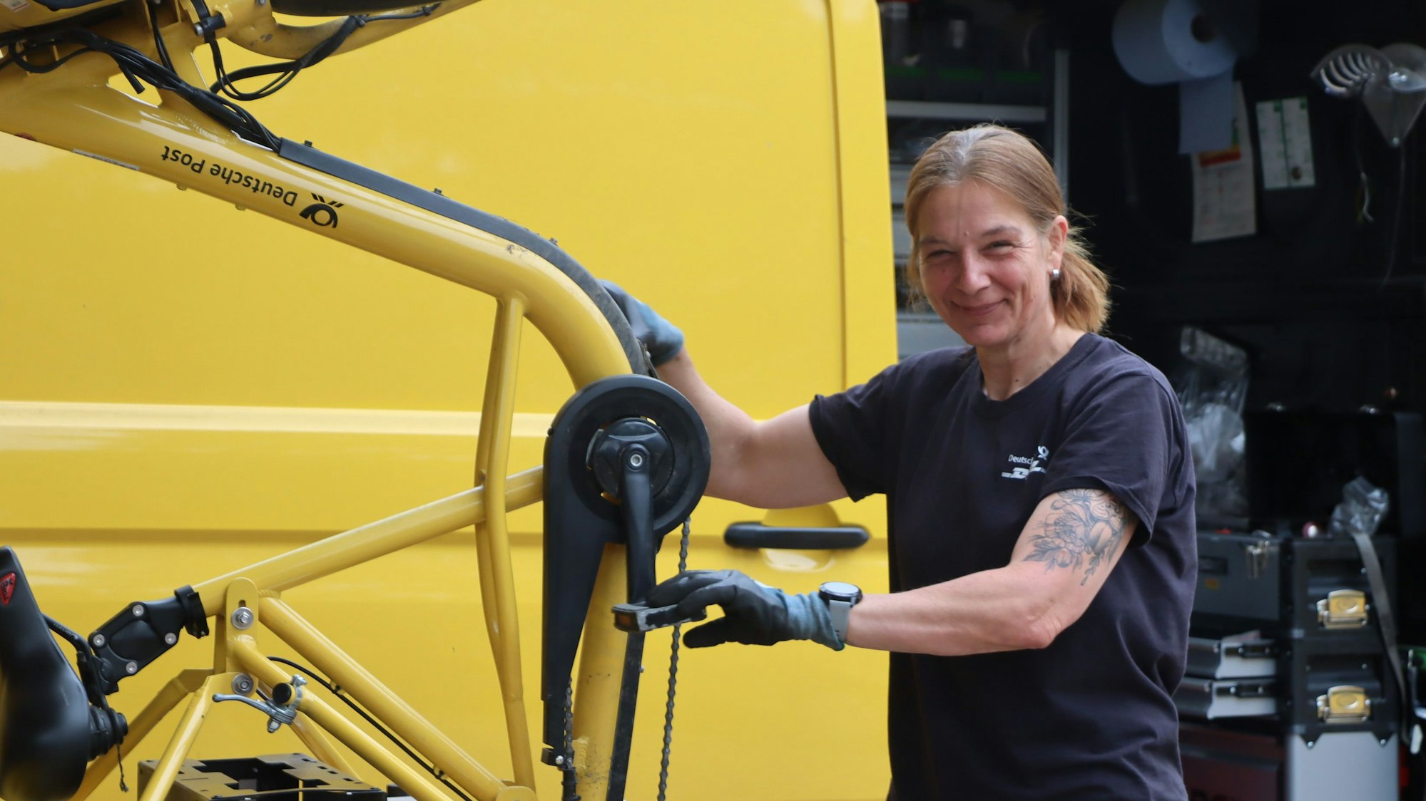 Das Bild zeigt Claudia Spohr mit ihrem Werkzeug-Wagen an einem Fahrrad.