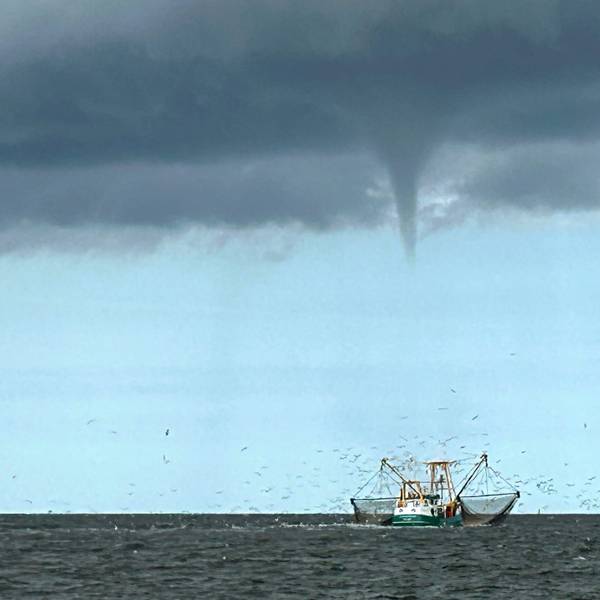 08.08.2024, Niedersachsen, Borkum: Das von einem Fischerboot aufgenommene Foto zeigt einen entstehenden mutmaßlichen Tornado vor der Nordseeinsel Borkum und ein Fischerboot.