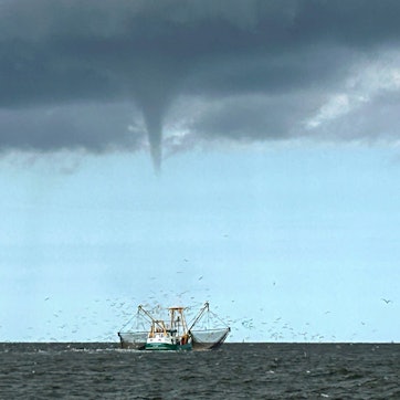 08.08.2024, Niedersachsen, Borkum: Das von einem Fischerboot aufgenommene Foto zeigt einen entstehenden mutmaßlichen Tornado vor der Nordseeinsel Borkum und ein Fischerboot.