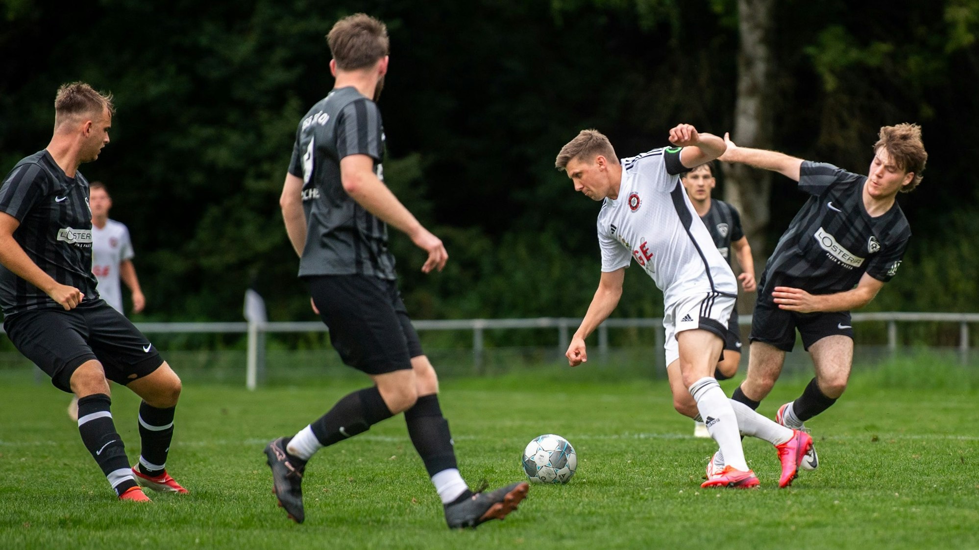 Ein Fußballer hat den Ball und dribbelt sich durch mehrere Gegenspieler hindurch.