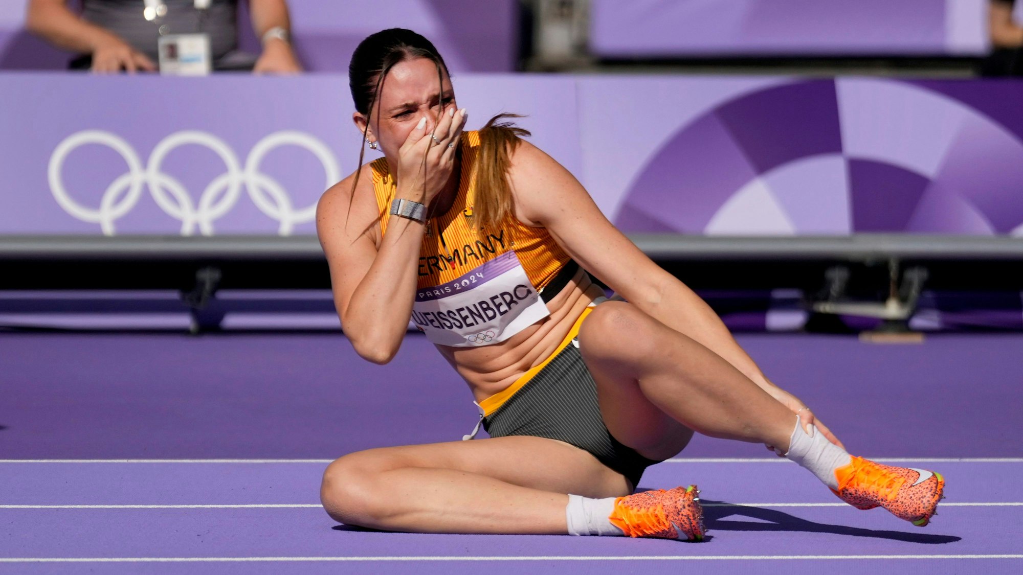 Sophie Weissenberg, of Germany, grabs her ankle after being injured while warming up for the women's heptathlon 100-meter hurdles at the 2024 Summer Olympics, Thursday, Aug. 8, 2024, in Saint-Denis, France.(AP Photo/Ashley Landis)