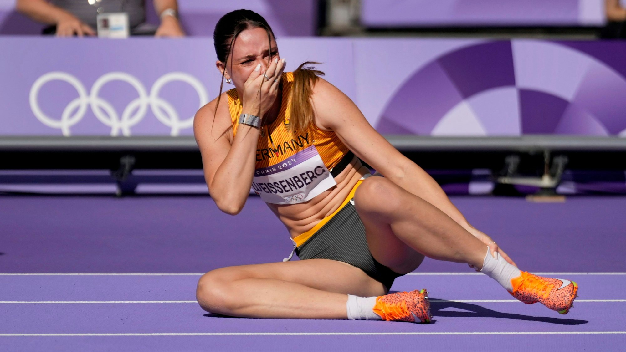 Sophie Weissenberg, of Germany, grabs her ankle after being injured while warming up for the women's heptathlon 100-meter hurdles at the 2024 Summer Olympics, Thursday, Aug. 8, 2024, in Saint-Denis, France.(AP Photo/Ashley Landis)