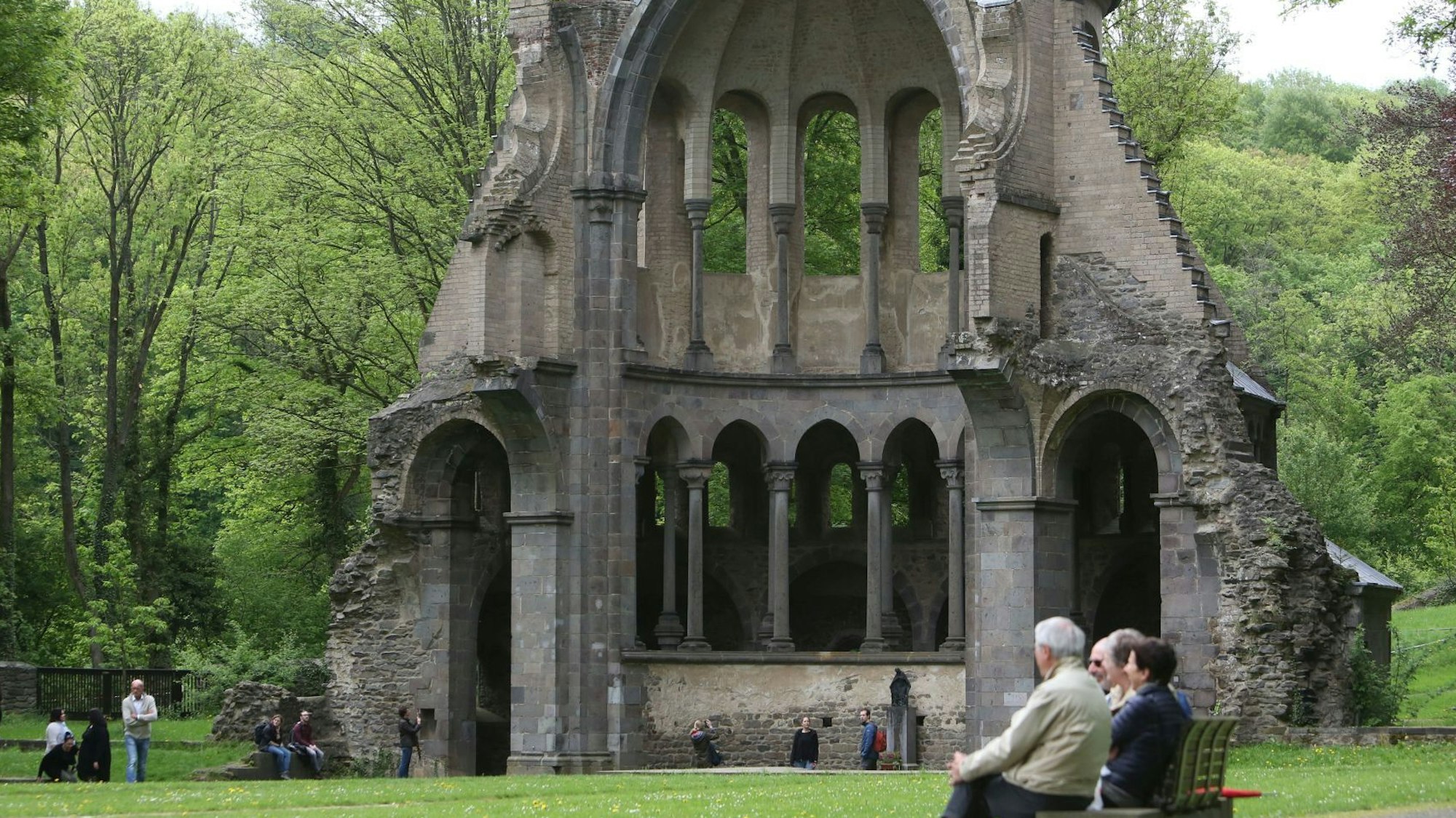 Menschen auf einer Bank vor der Chorruine des Klosters Heisterbach-