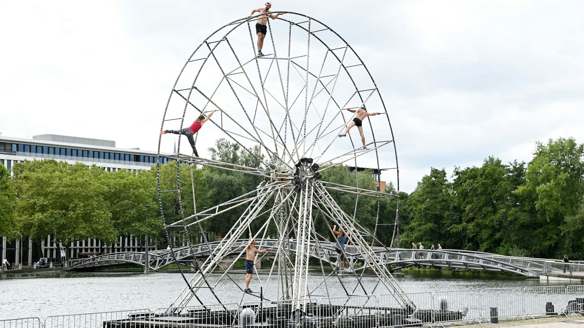 Das Bild zeigt ein Riesenrad mit vier Menschen darauf.