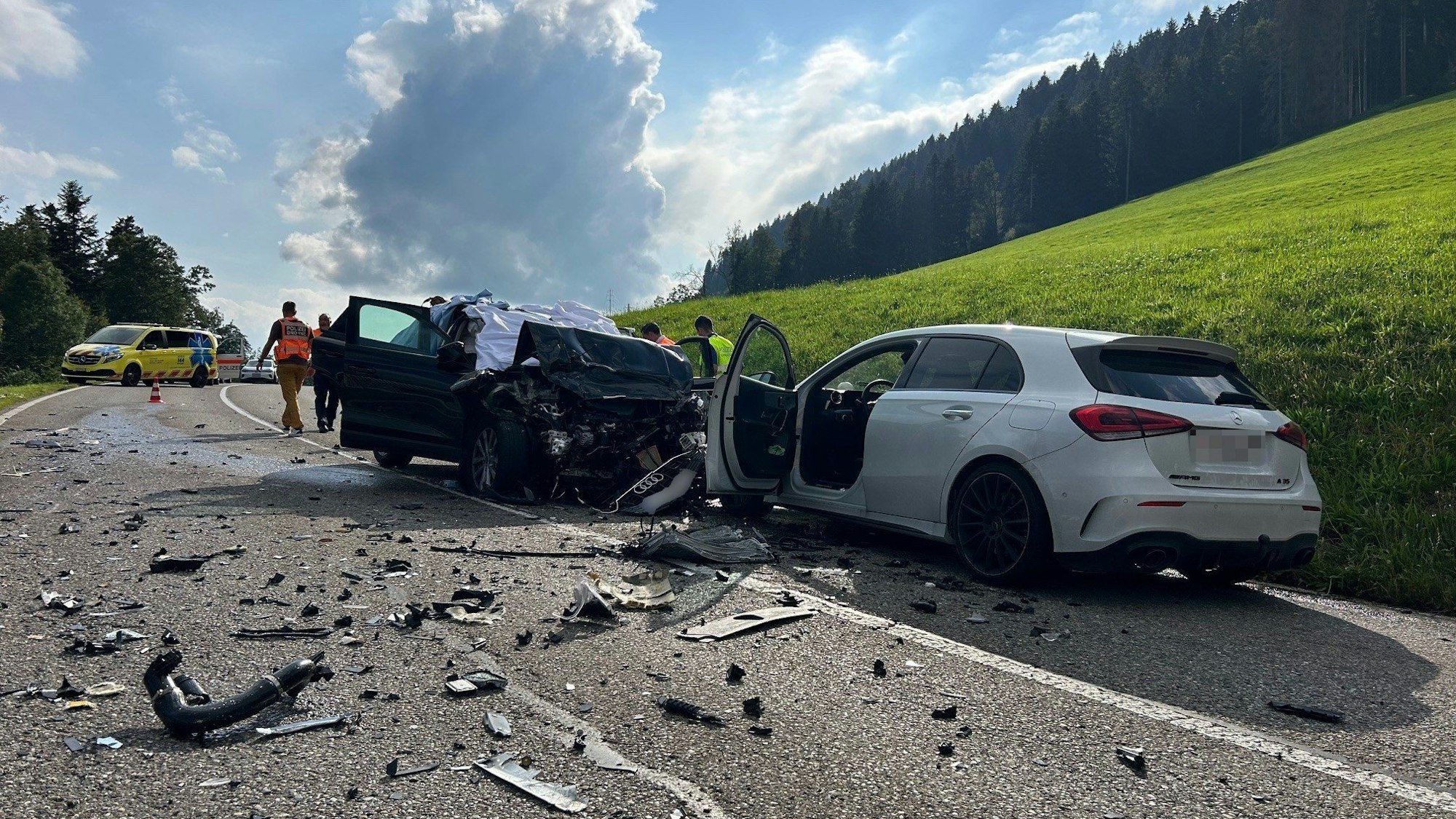 HANDOUT - 08.08.2024, Schweiz, Wattwil: Beteiligte Unfallfahrzeuge stehen nach dem Zusammenstoß eines Autos mit einem Bus am Straßenrand. Drei Deutsche sind dabei ums Leben gekommen. Das Auto des Deutschen sei über die Mittellinie geraten und dann frontal mit einem Bus zusammengestoßen. Durch die Wucht der Kollision wurde das Auto der Deutschen in die Gegenrichtung und dort frontal gegen das Auto einer 49-jährigen Frau geschleudert. Foto: Kantonspolizei St.Gallen/dpa - ACHTUNG: Nur zur redaktionellen Verwendung im Zusammenhang mit der aktuellen Berichterstattung und nur mit vollständiger Nennung des vorstehenden Credits +++ dpa-Bildfunk +++