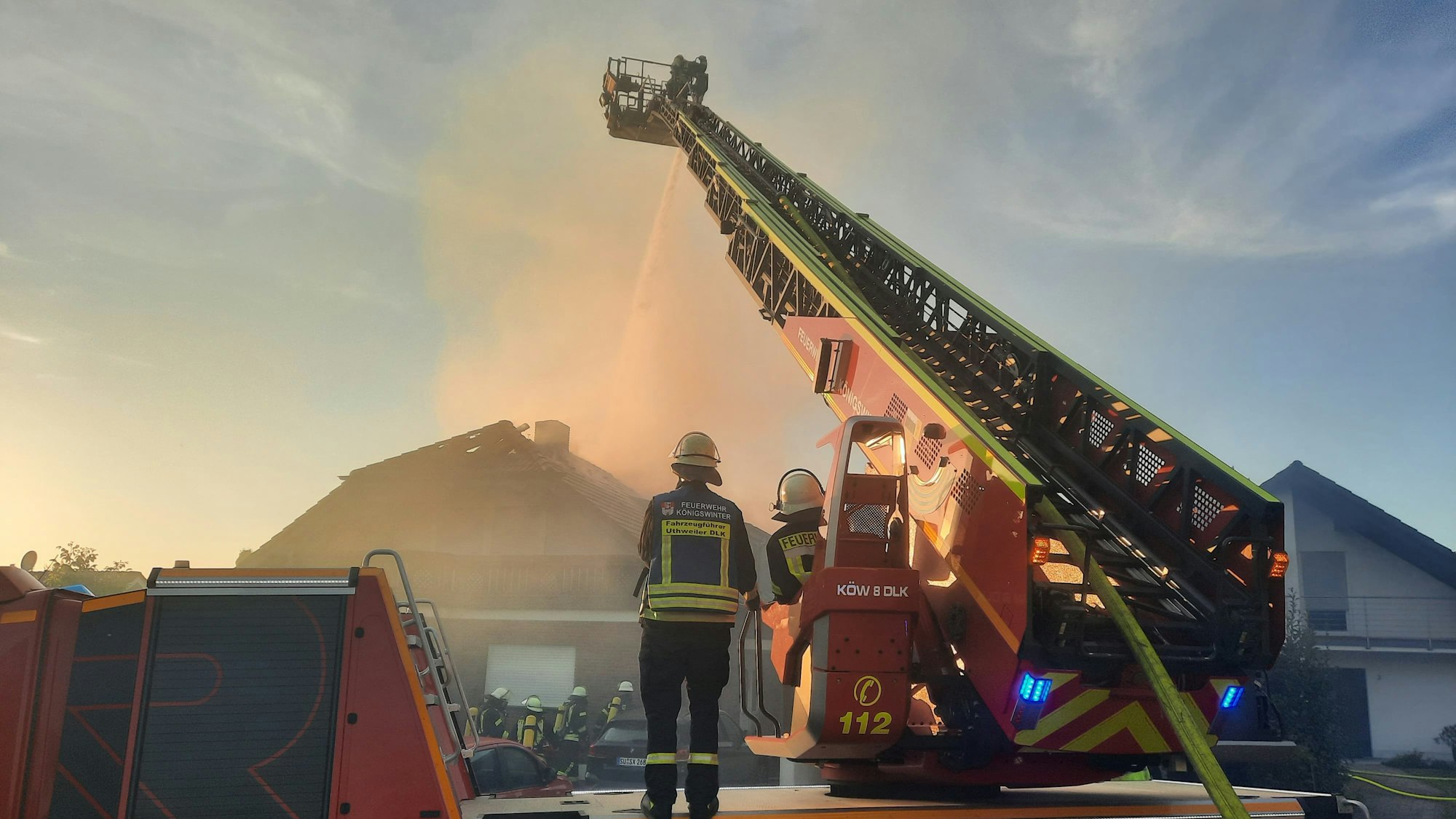 Von einer Drehleiter aus löschen Feuerwehrleute ein brennendes Haus.