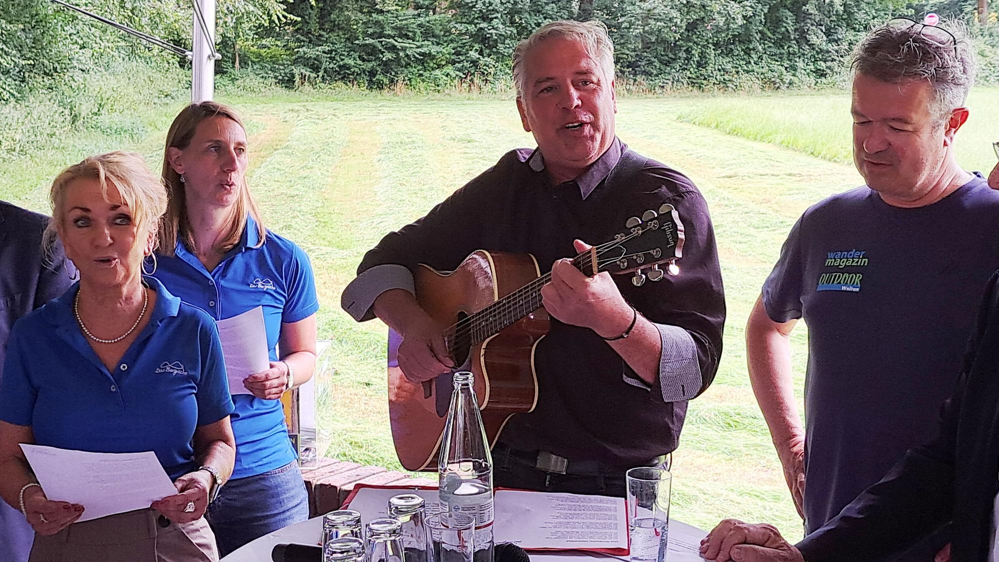 Odenthals Bürgermeister Robert Lennerts stimmt mit der Gitarre das Bergische Heimatlied an.