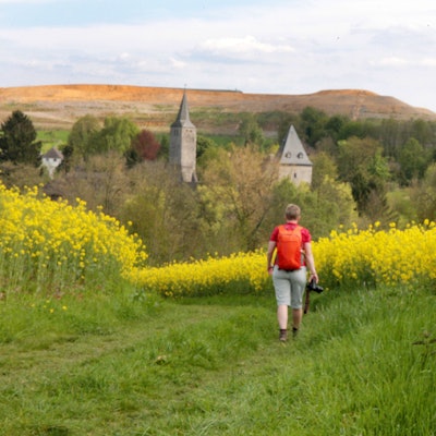 Eine Frau geht auf dem Bergischen Weg über eine Wiese.