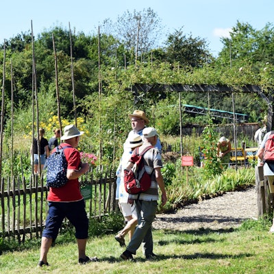 Mehrere Frauen und Männer schlendern durch einen Museumsgarten.