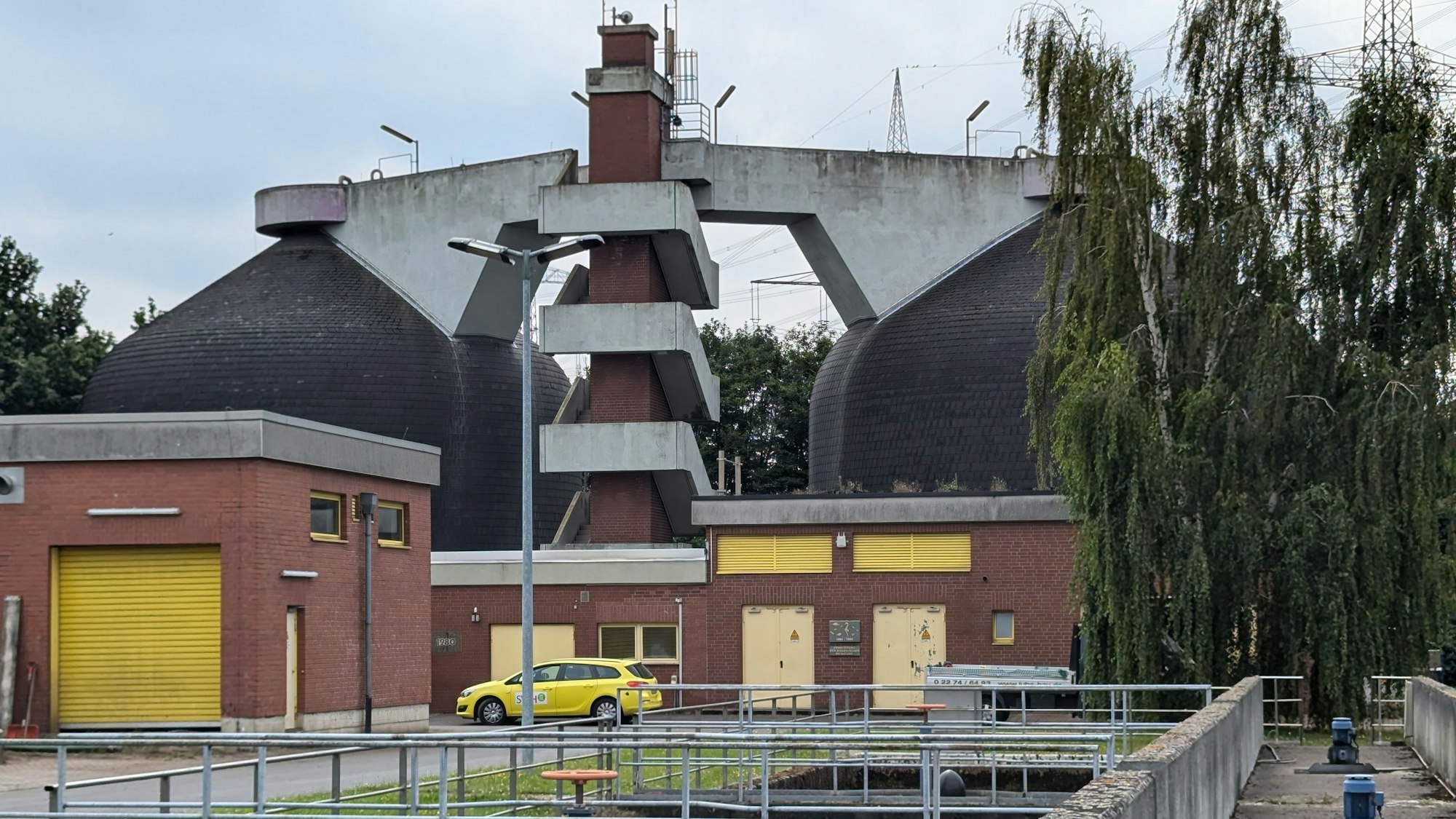 Das Foto zeigt die markanten Faulbehälter hinter einem Betriebsgebäude.