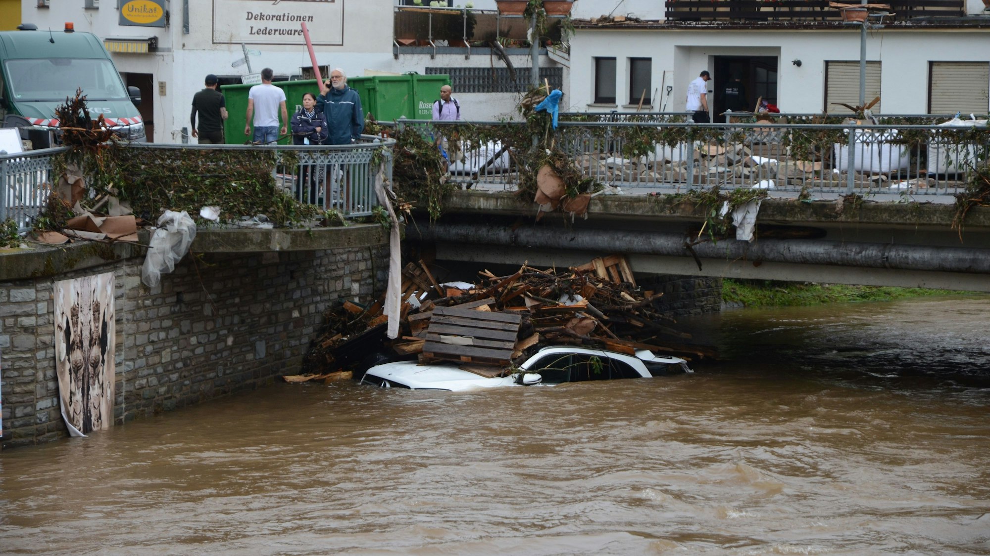 Ein Auto und Holz liegen nach der Flutkatastrophe 2021 in der Olef in Gemünd an einer Brücke.