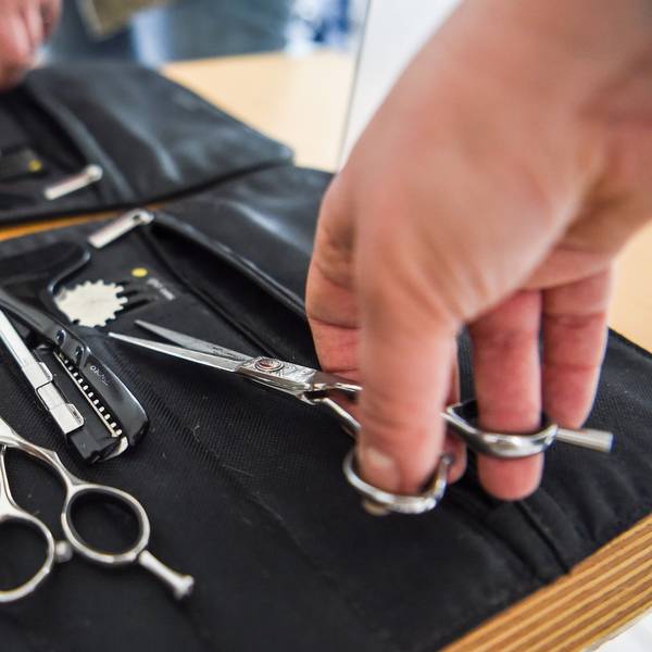 Eine Friseurin nimmt eine Haarschere aus ihrer Tasche. (Archivbild)